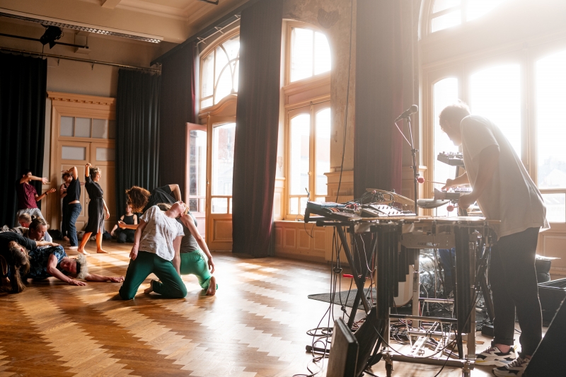 Foto van een groep dansende mensen met muzikant met keyboard en muzikant met drumstel op de voorgrond, beeld van deze Open Dance Jam